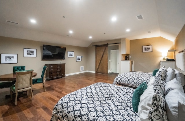 bedroom featuring dark hardwood / wood-style flooring, vaulted ceiling, and a barn door