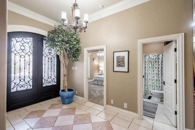 tiled entrance foyer featuring french doors, a healthy amount of sunlight, crown molding, and an inviting chandelier