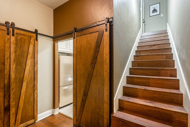 stairs with a barn door and hardwood / wood-style floors