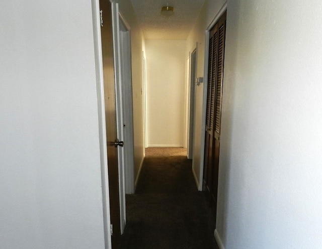 hallway with dark colored carpet