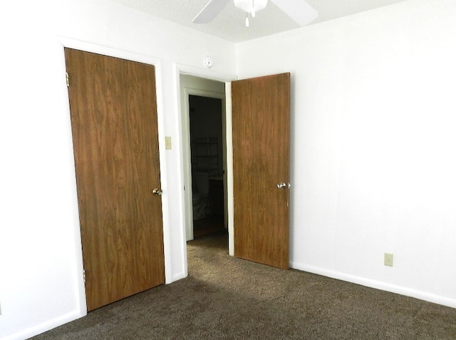 unfurnished bedroom featuring a closet, ceiling fan, and dark colored carpet