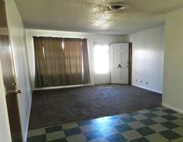 carpeted empty room featuring a textured ceiling