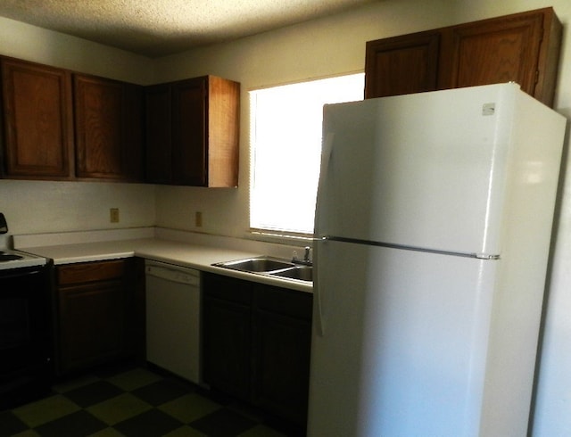 kitchen featuring white appliances, a textured ceiling, and sink