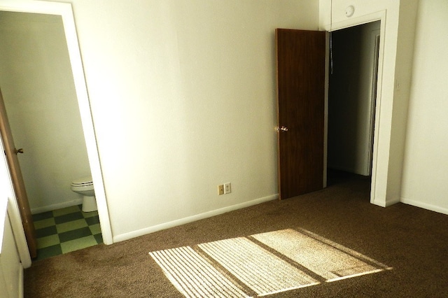 unfurnished bedroom with ensuite bath and dark carpet