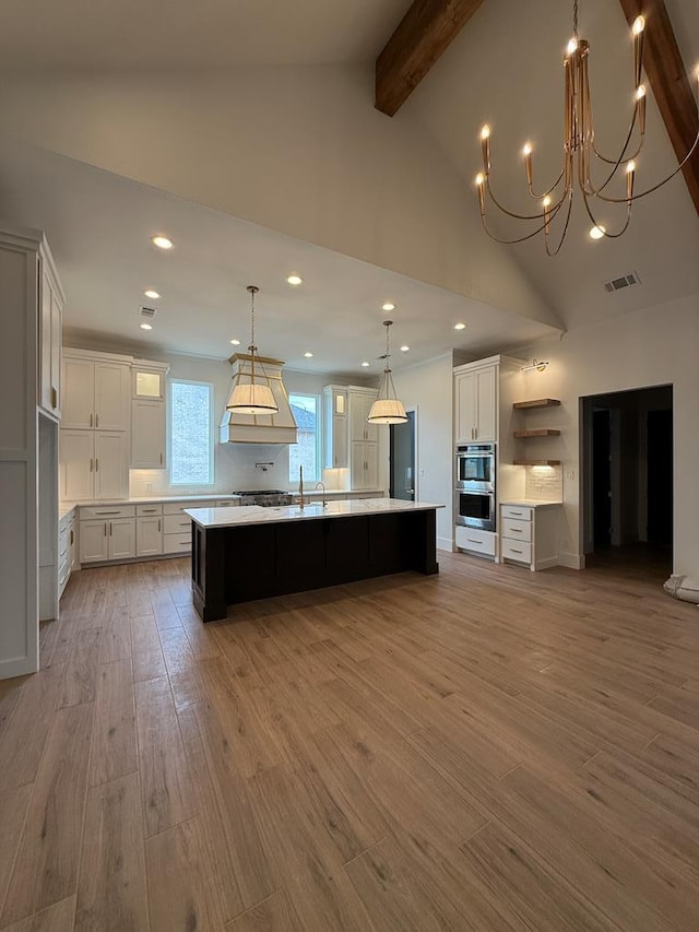 kitchen with white cabinetry, decorative light fixtures, light hardwood / wood-style flooring, and a spacious island