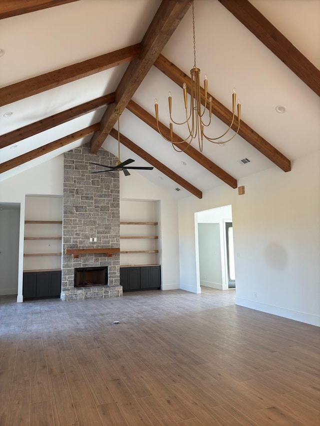 unfurnished living room featuring vaulted ceiling with beams, ceiling fan with notable chandelier, built in features, and a stone fireplace