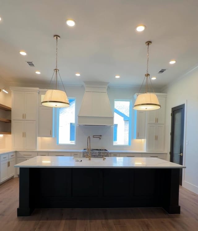 kitchen with white cabinets, plenty of natural light, a spacious island, and premium range hood