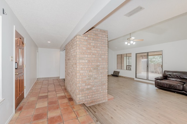 hall featuring vaulted ceiling, a textured ceiling, and light wood-type flooring