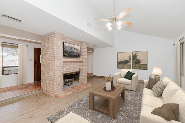 living room featuring a ceiling fan, wood finished floors, a fireplace, and visible vents