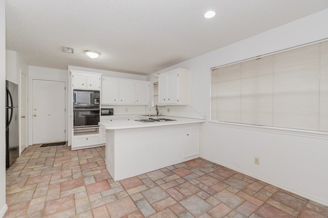 kitchen with sink, white cabinetry, black appliances, a textured ceiling, and kitchen peninsula