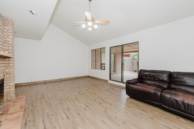 living area featuring baseboards, high vaulted ceiling, a fireplace, ceiling fan, and light wood-style floors