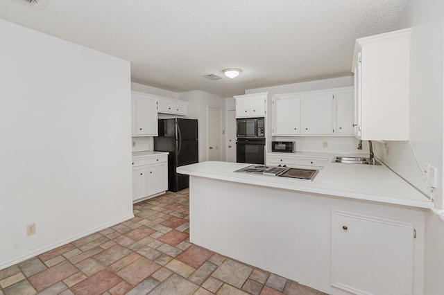 kitchen with light countertops, a peninsula, stone finish floor, black appliances, and a sink