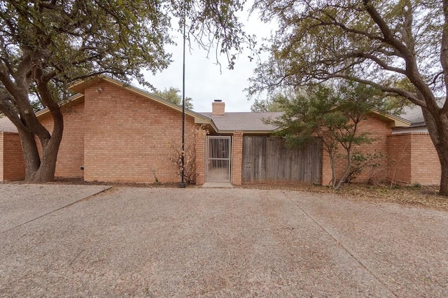 view of side of property with brick siding, a chimney, and fence