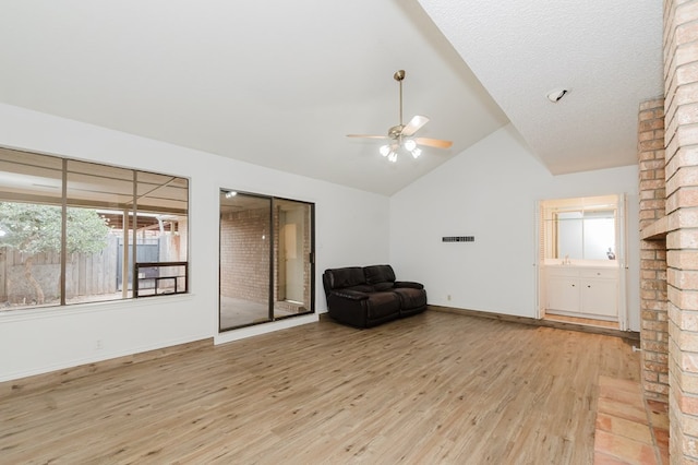 living area with lofted ceiling, a textured ceiling, light hardwood / wood-style flooring, and ceiling fan