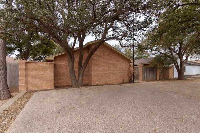 view of side of property featuring brick siding and fence