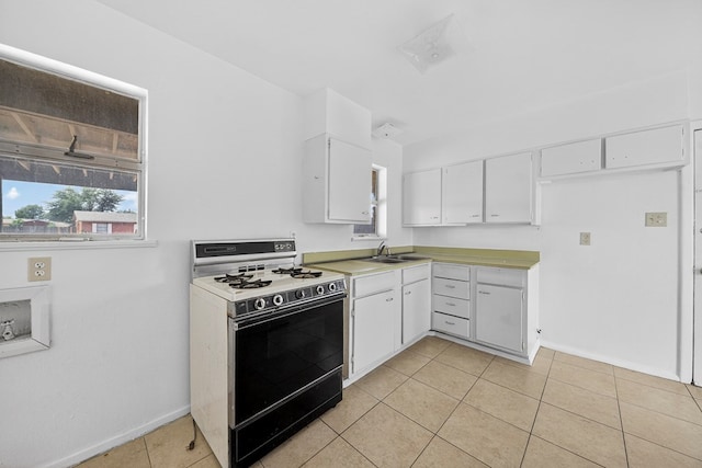 204 Acklen, Midland, TX 79703 - kitchen with gas stove, white cabinets, light tile patterned floors, and light countertops