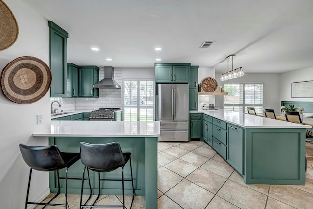 3513 Stanolind Ave, Midland, TX 79707 - kitchen featuring green cabinets, stainless steel appliances, a peninsula, wall chimney range hood, and light countertops