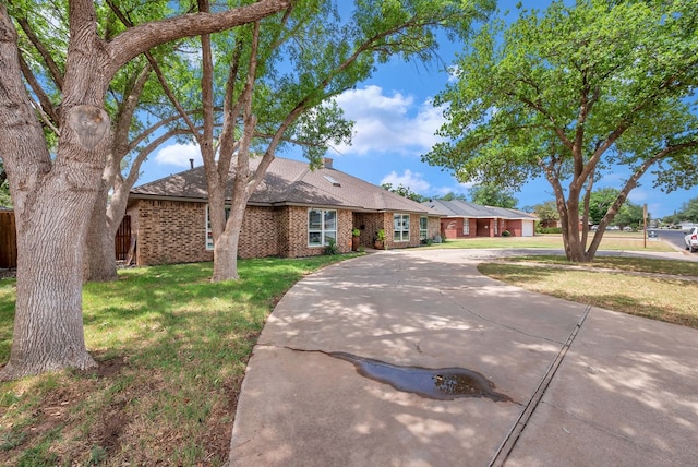 3513 Stanolind Ave, Midland, TX 79707 - view of front of home featuring brick siding, curved driveway, a front lawn, and a shingled roof