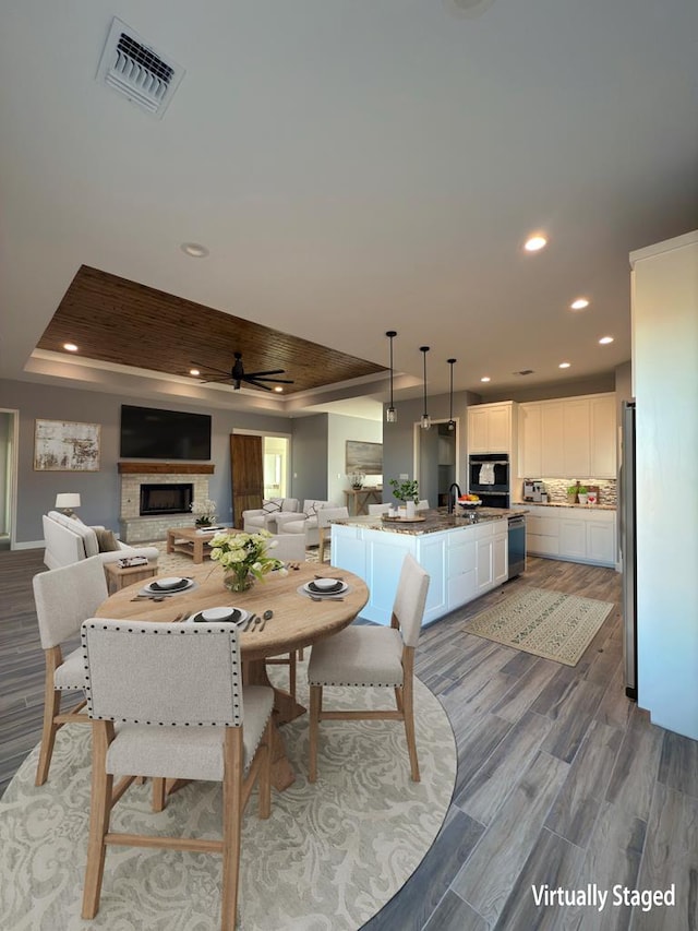 dining area with wood-type flooring, sink, and a tray ceiling