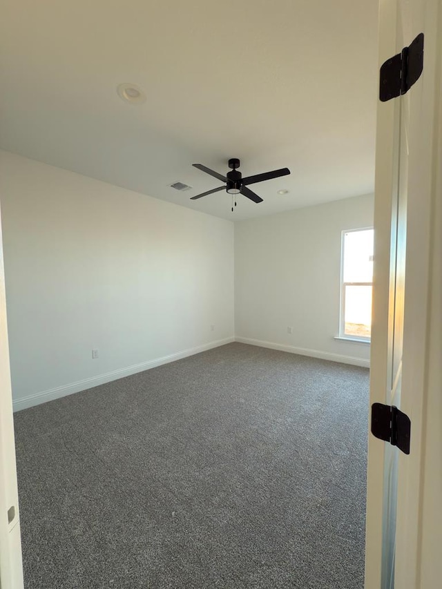 empty room with dark colored carpet and ceiling fan