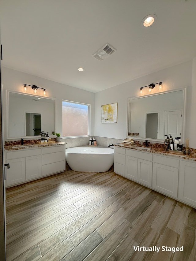 bathroom featuring vanity, a tub to relax in, and hardwood / wood-style flooring