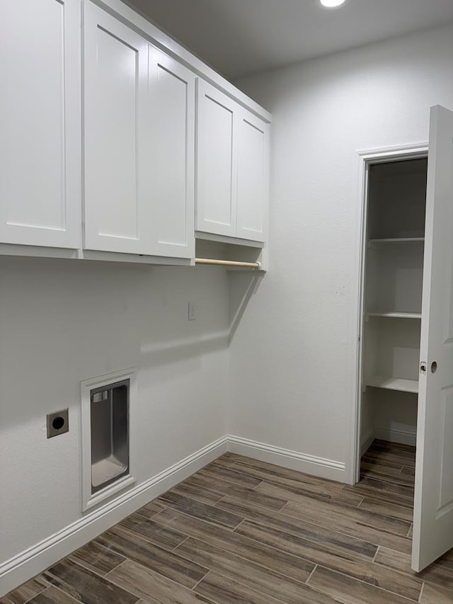 laundry room with dark wood-type flooring, cabinets, and electric dryer hookup