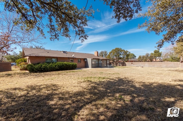 exterior space with a yard, a chimney, fence, and brick siding