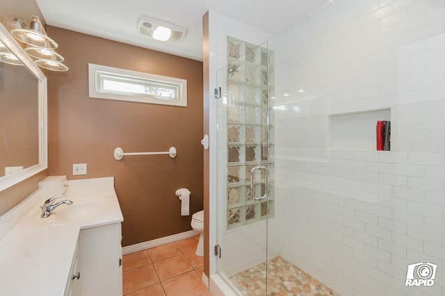 bathroom featuring toilet, a shower stall, vanity, tile patterned flooring, and baseboards