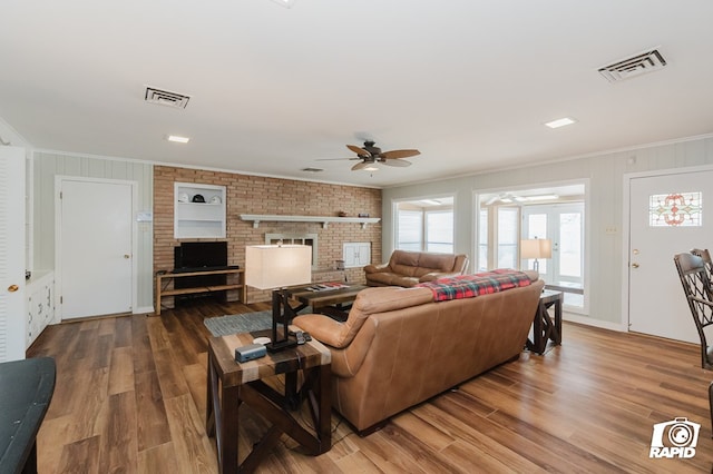 living area featuring ornamental molding, wood finished floors, and visible vents