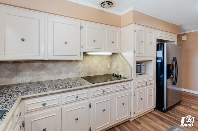 kitchen with visible vents, white cabinets, stainless steel fridge with ice dispenser, black electric cooktop, and crown molding