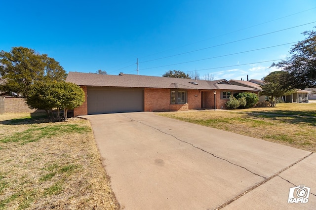 ranch-style house with driveway, brick siding, an attached garage, and a front yard