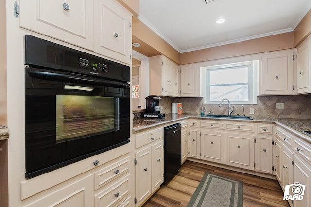 kitchen featuring light stone countertops, a sink, ornamental molding, decorative backsplash, and black appliances