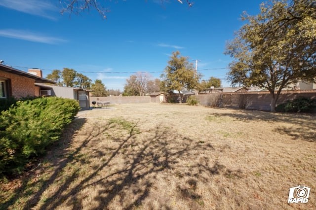 view of yard with a storage unit, fence, and an outdoor structure