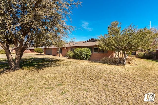 ranch-style home featuring brick siding, an attached garage, and a front yard