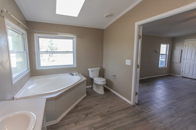 bathroom featuring lofted ceiling with skylight, crown molding, hardwood / wood-style flooring, toilet, and a tub