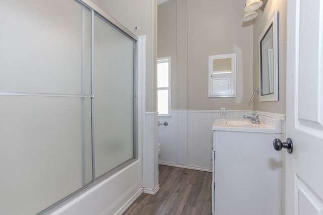 full bathroom featuring shower / bath combination with glass door, hardwood / wood-style floors, vanity, and toilet