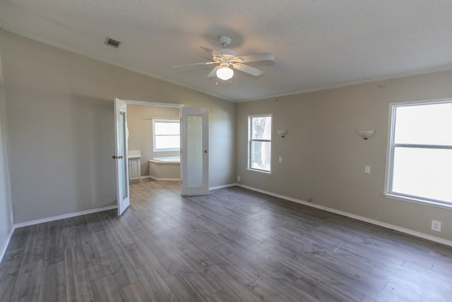 empty room with a textured ceiling, vaulted ceiling, ceiling fan, crown molding, and dark wood-type flooring