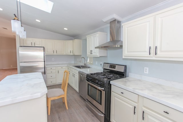 kitchen featuring lofted ceiling with skylight, wall chimney range hood, sink, appliances with stainless steel finishes, and decorative light fixtures