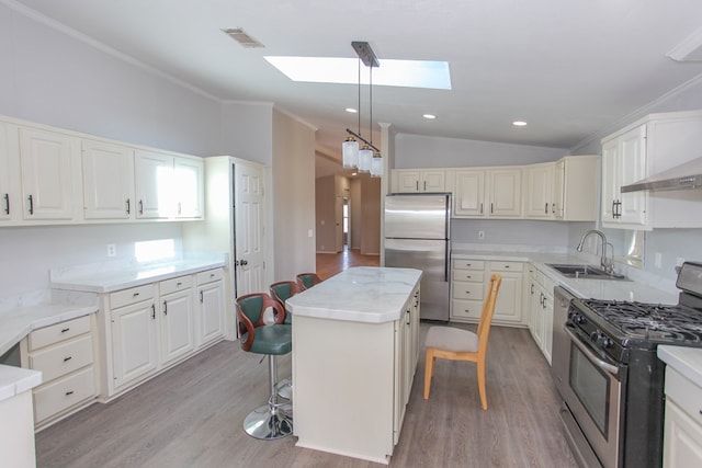 kitchen featuring lofted ceiling with skylight, sink, a breakfast bar area, a kitchen island, and stainless steel appliances