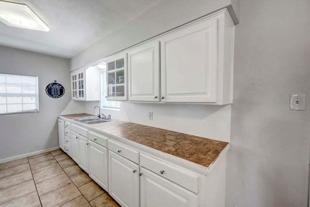 kitchen featuring white cabinetry, sink, tile counters, and plenty of natural light