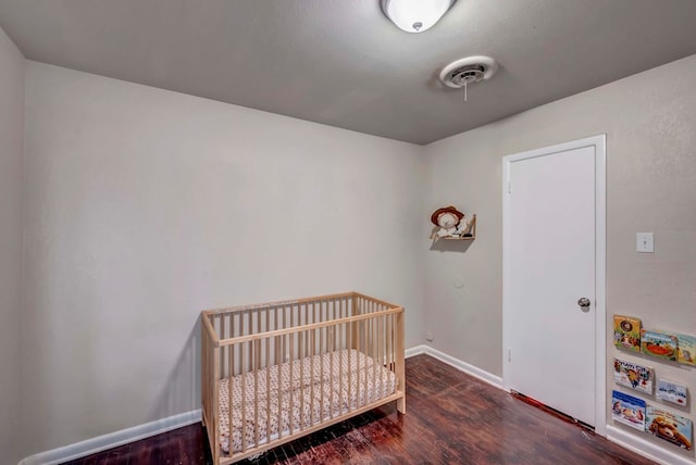 bedroom featuring dark hardwood / wood-style flooring and a nursery area