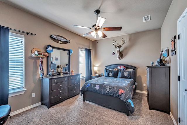 carpeted bedroom featuring ceiling fan, a textured ceiling, and multiple windows