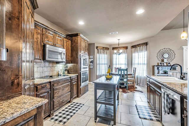 kitchen featuring backsplash, a chandelier, decorative light fixtures, and appliances with stainless steel finishes