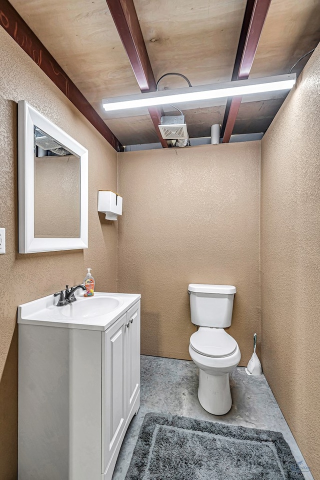 bathroom featuring beamed ceiling, vanity, and toilet