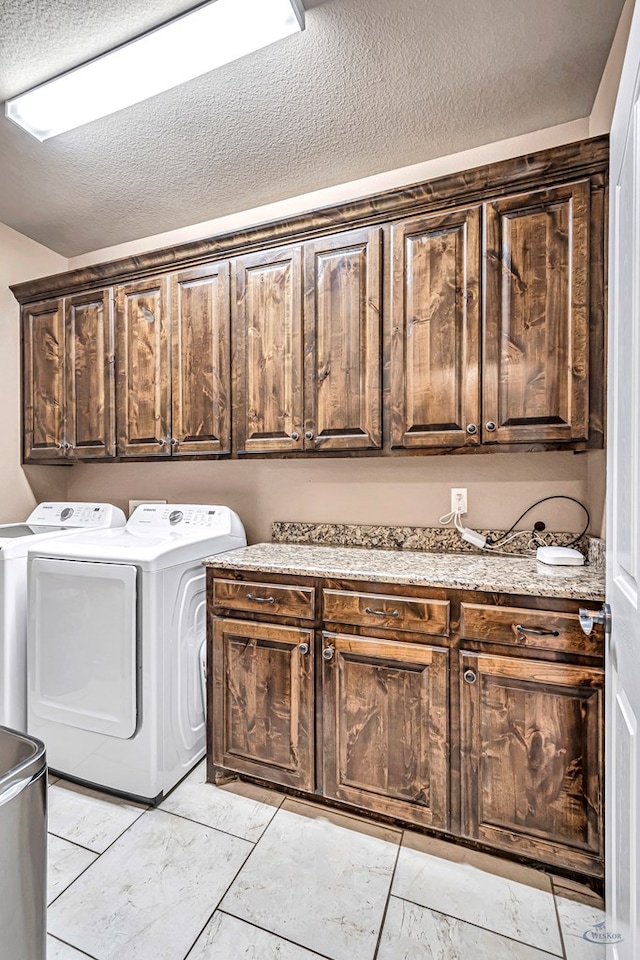 washroom with washer and dryer, cabinets, and a textured ceiling