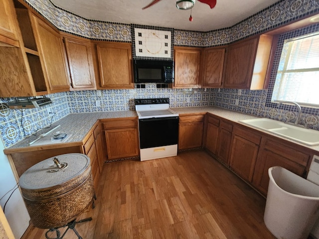 kitchen with ceiling fan, sink, white range oven, decorative backsplash, and light wood-type flooring