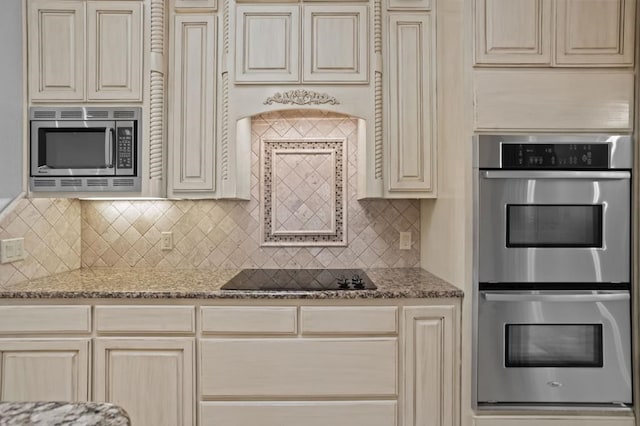 kitchen with cream cabinets, appliances with stainless steel finishes, decorative backsplash, and light stone counters