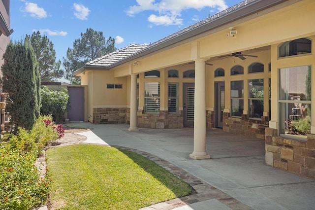 exterior space featuring a ceiling fan, stone siding, a patio, and stucco siding