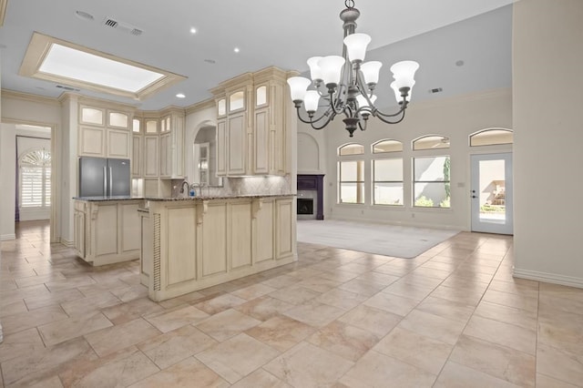 kitchen with a breakfast bar, cream cabinetry, crown molding, freestanding refrigerator, and open floor plan