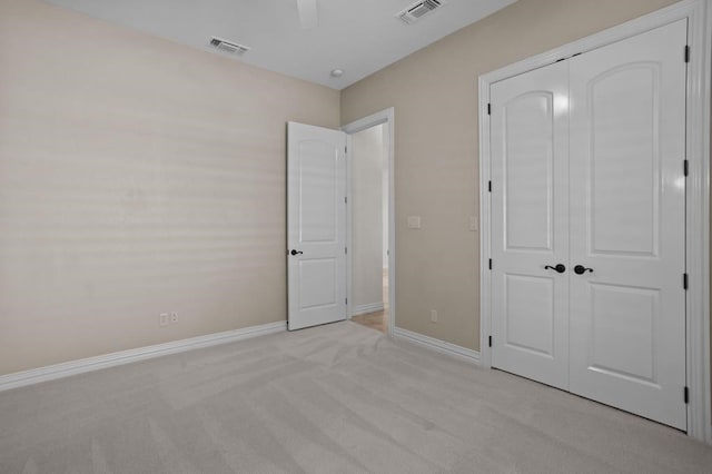 unfurnished bedroom featuring a closet, visible vents, light carpet, and baseboards